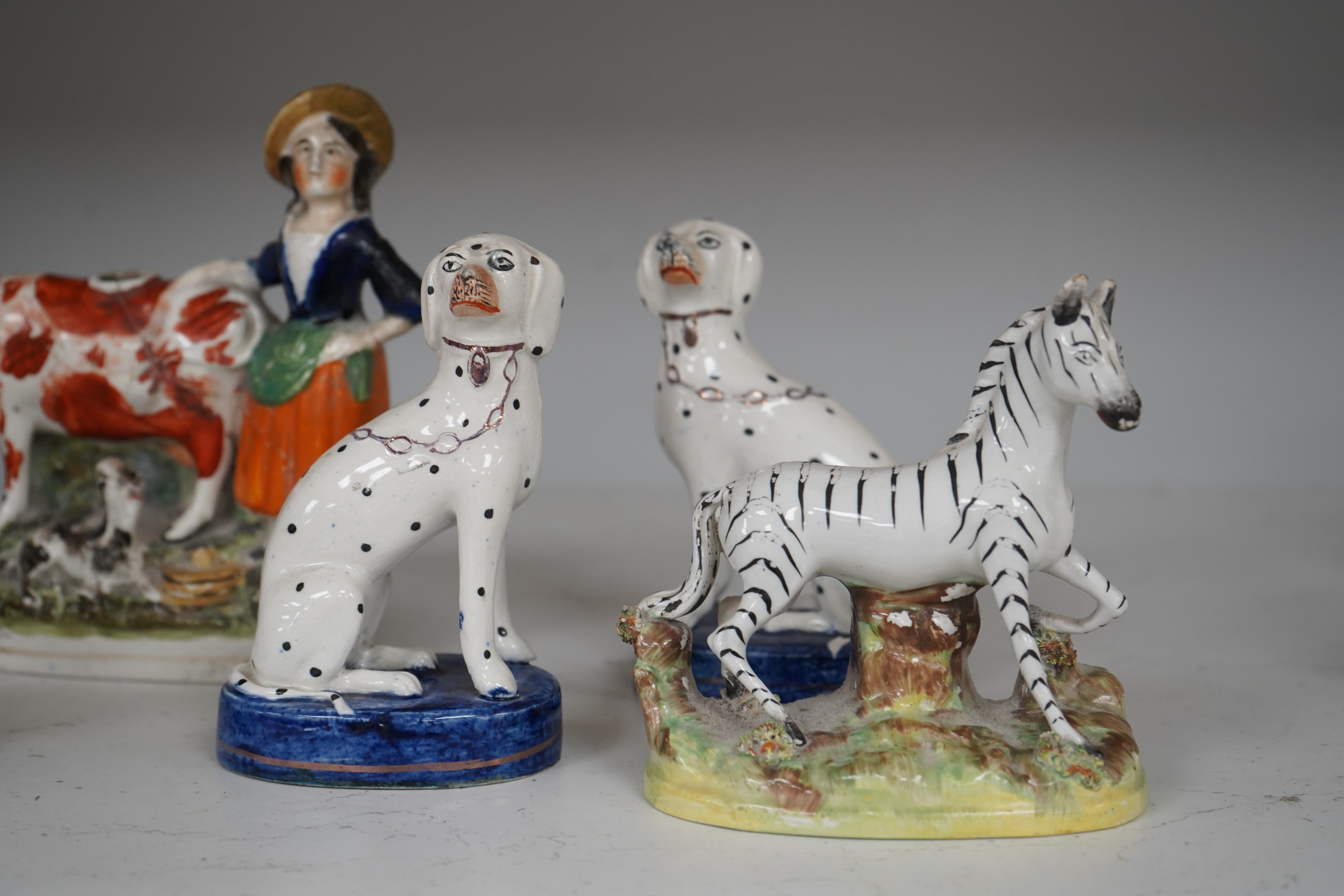 Eight Staffordshire figures to include a pair of Dalmatian’s and a cow creamer figure, largest 18cm wide. Condition - varies, poor to good